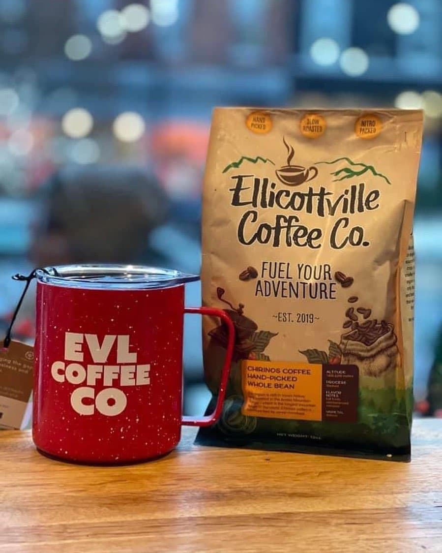 Ellicottville Coffee Co. hand-picked whole bean bag beside a red EVL Coffee Co. camp mug